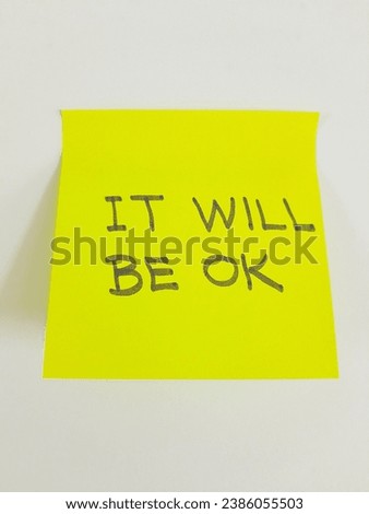 Message written on a yellow sticky note, 'It will be ok', on blank sheet of white paper with copy space