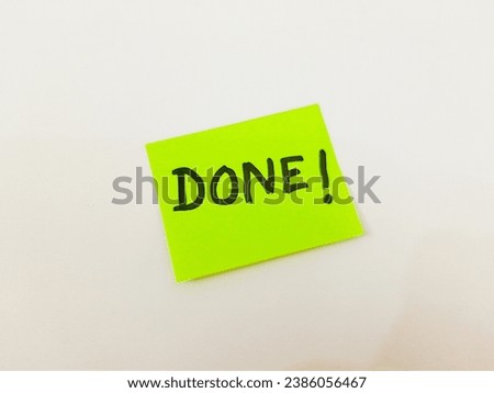 Message written on a green sticky note, 'Done', on blank sheet of white paper with copy space