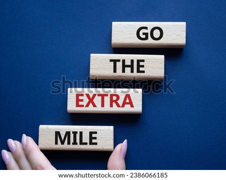 Go the extra mile symbol. Wooden blocks with words Go the extra mile. Businessman hand. Beautiful deep blue background. Business and Go the extra mile concept. Copy space.