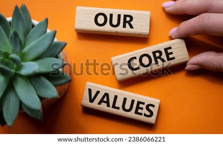 Our core values symbol. Concept words Our core values on wooden blocks. Beautiful orange background with succulent plant. Businessman hand. Business and Our core values concept. Copy space.