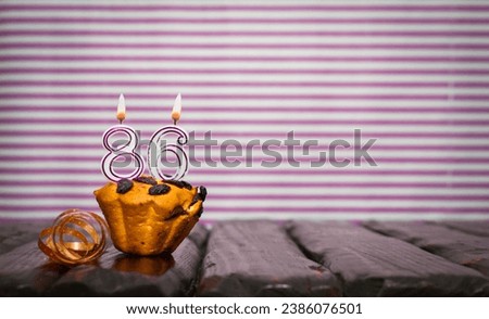 Birthday number 86. Date of birth with number of candles, copy space. Anniversary background with cake or muffin with burning candles. Greeting card.