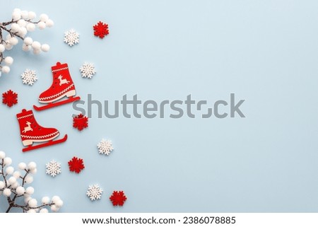 Ice skates with white and red snowflakes and white berries on a blue background, Merry Christmas and Happy New Year concept, top view, copy space