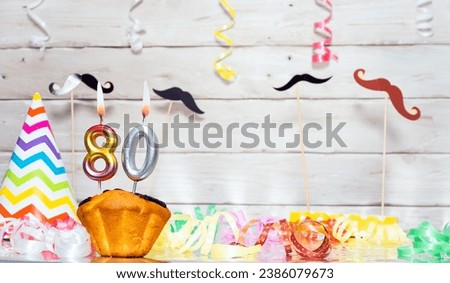 Birthday with number  80. Date of birth with number and candles, copy space. Anniversary background with cake or muffin with burning candles. Keative postcard congratulations.
