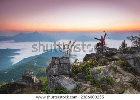 Young woman  in red jacket hiking on the high mountain, Doi Pha Tang, Chiang Rai province, border  of  Thailand and Laos.