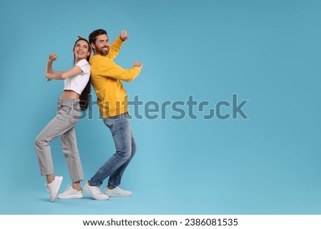 Happy couple dancing together on light blue background, space for text