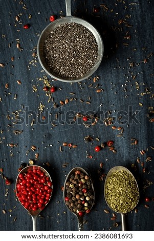 Old metal spoons with different kind of spices on black background. Flat lay. Top view. Food concept. Dark mood food photography.