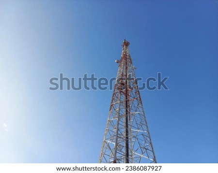 The tower is red and white as a transmitter for radio, internet and other signals under a bright blue sky