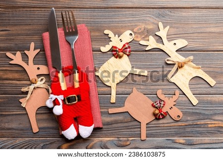 New year set of fork and knife on napkin. Top view of christmas decorations and reindeer on wooden background. Close up of holiday family dinner concept.