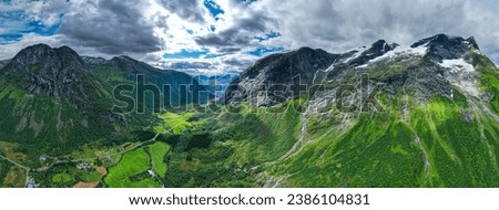Aerial view of the epic mountains of Norway Cascading into the Fjords with fresh summertime green as Glaciers melt at the summit