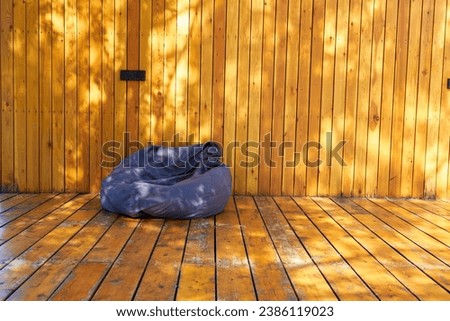 Photo a gray bag chair on the background of a wooden terrace. A place for a summer vacation. Outdoor furniture.