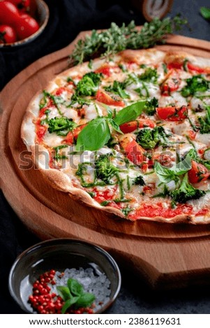Vegetable pizza with herbs, broccoli, tomatoes, basil and pesto sauce. Close-up, selective focus