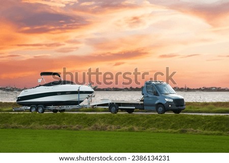 Luxury Boat Journey on the Road at Sunset. Modern motorboat delivery on the driveway. Sunset sky. Royalty-Free Stock Photo #2386134231
