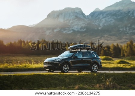 Expensive family SUV with Luggage box mounted on the roof. Extra Capacity for the Road. Black SUV with Roof Rack. Royalty-Free Stock Photo #2386134275