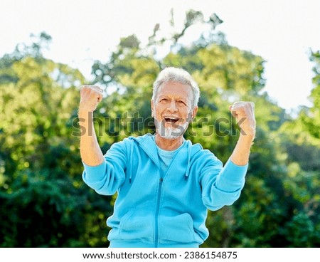 Smiling active senior man jogging exercising and having fun and celebrating success rasing hands taking a break in the park, concept of competition, winning, victory and strength Royalty-Free Stock Photo #2386154875