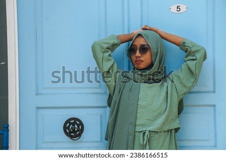 Beautiful Muslim woman wearing a hijab wearing a green dress and glasses