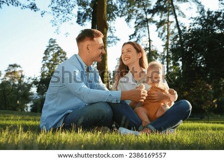 Parents with their cute daughter spending time together in park on summer day Royalty-Free Stock Photo #2386169557