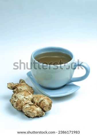Cup of hot ginger tea with ginger root on white background