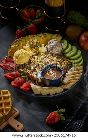 A plate of waffles with chocolate and fruits on a black background