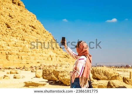 Woman tourist takes photographs of the Pyramid of Khafre.  Giza, Egypt - October 16, 2023  Royalty-Free Stock Photo #2386181775