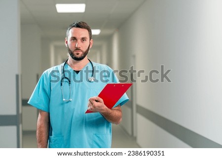 Portrait of a smiling doctor with a beard and a stethoscope on his neck holds a folder with documents and looks at camera