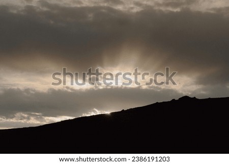 Colorado rocky mountain scape silhouette background with moody grey clouds and bright sun shining through dark clouds on Trail Ridge Road in Rocky Mountain National Park 
