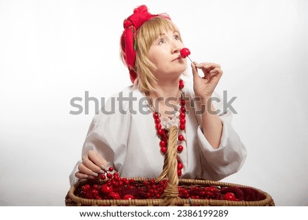 Portrait of heerful funny adult mature woman solokha with red berries. Female model in clothes of national ethnic Slavic style. Stylized Ukrainian, Belarusian or Russian woman in comic photo shoot