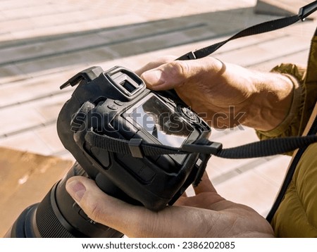 Hands holding photo camera, adjusting for shooting
