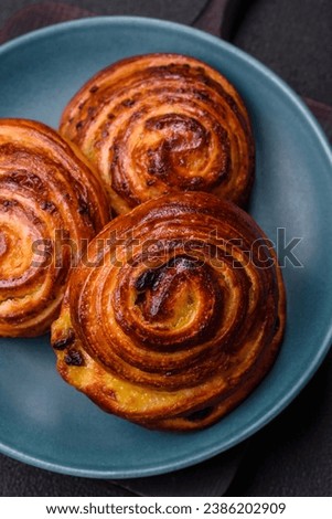 Delicious baked cinnamon raisin rolls in the form of rolls on a dark concrete background