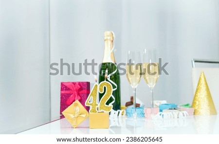Date of birth with number  42. Festive Champagne in glasses with gift boxes, anniversary postcard. Happy birthday golden candles.