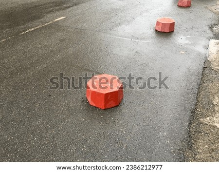 Red parking posts stand on the asphalt near the sidewalk
