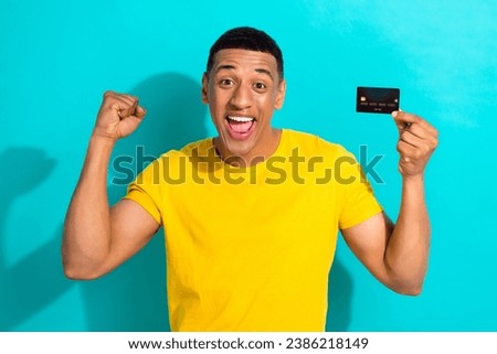 Photo of young man wear bright t-shirt raise fist up hooray receive his first salary with no taxes isolated on aquamarine color background