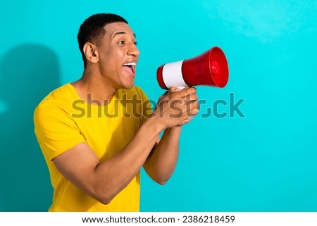 Photo of good mood excited man dressed yellow t-shirt screaming loud speaker empty space isolated turquoise color background