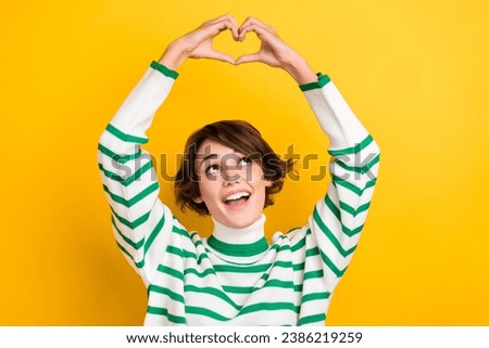 Photo of cheerful nice girl beaming smile look arms fingers demonstrate heart symbol wear turtleneck isolated on yellow color background