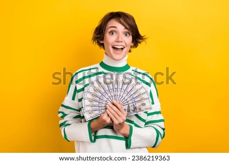Photo of excited impressed girl dressed striped sweater rising money fan isolated yellow color background