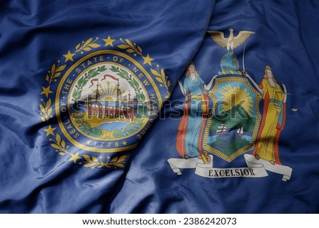 big waving colorful national flag of new york state and flag of new hampshire state . macro