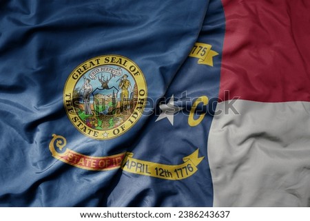 big waving colorful national flag of north carolina state and flag of idaho state . macro