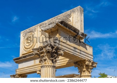 Upper part of the monumental portico with attic with metopes of the old Municipal Forum of Augusta Emerita in Merida, with two medallions with the heads of Medusa, Jupiter-Amon and Cariatides. Royalty-Free Stock Photo #2386244477