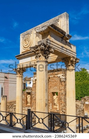 Monumental portico of the old Municipal Forum of Augusta Emerita in Merida, with two medallions with heads of Medusa and Jupiter-Amon and two classical Roman sculptures framed in two windows. Royalty-Free Stock Photo #2386245369