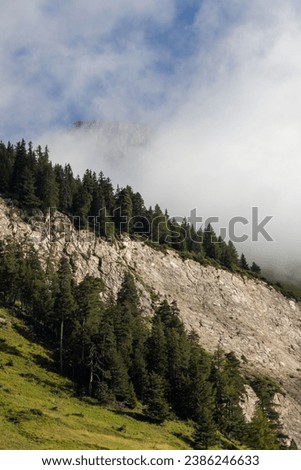Clouds hanging on Swiss alps mountains terrain with thick clouds hiking in the mountains