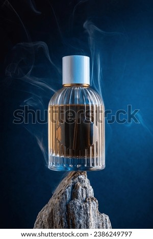 Glass bottle of perfume stand on the rock with smoke. Dramatic creative photography for perfumery advrtising