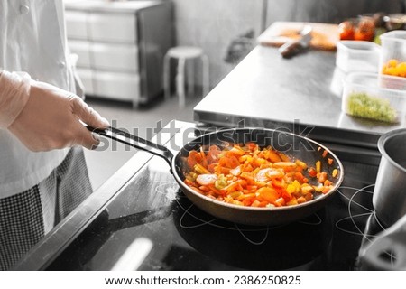 cooking food, profession and people concept - close up of male chef with frying pan stewing vegetables at restaurant kitchen Royalty-Free Stock Photo #2386250825