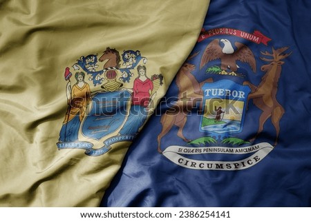 big waving colorful national flag of michigan state and flag of new jersey state . macro