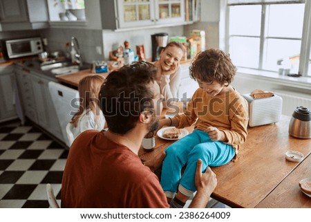Happy family having fun in kitchen during breakfast Royalty-Free Stock Photo #2386264009
