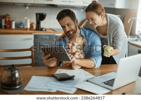 Young family using tablet with documents on desk Royalty-Free Stock Photo #2386264817