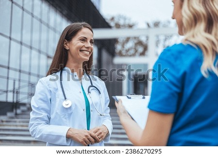 Shot of two medical practitioners using a clipboard together in a hospital. Experienced doctor sharing point of view with colleague. Female nurse and  female doctor discuss patient care