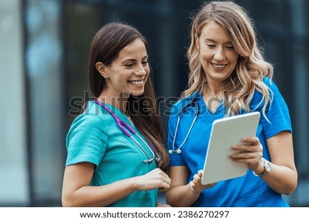 Researching news on a specific disease. Shot of two medical practitioners using a digital tablet together in a hospital. Healthcare staff having discussion in a hallway of private clinic.