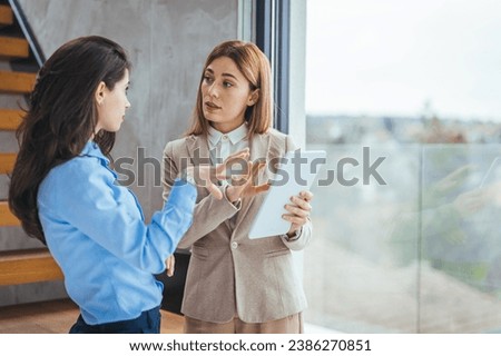 Portrait of two young business woman having a meeting or presentation and seminar standing in the office. Portrait of a young business woman talking. 