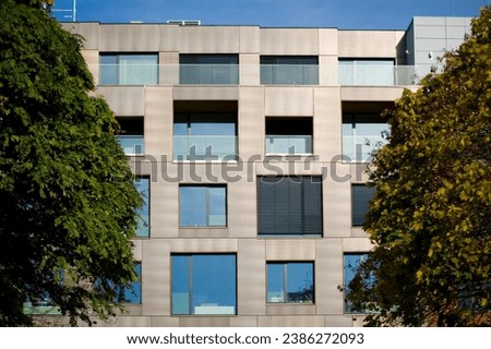 Modern facade of an office building in Poznan behind trees.