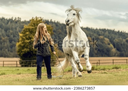 A young woman and her icelandic horse working and cuddle together, equestrian natural horsemanship concept Royalty-Free Stock Photo #2386273857