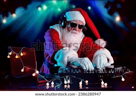 DJ Santa Claus mixing tracks in a nightclub at a Christmas and New Year party or Corporate events. Senior disc jockey as Santa listening music, headphones, laptop, mixer controller player, turntable.